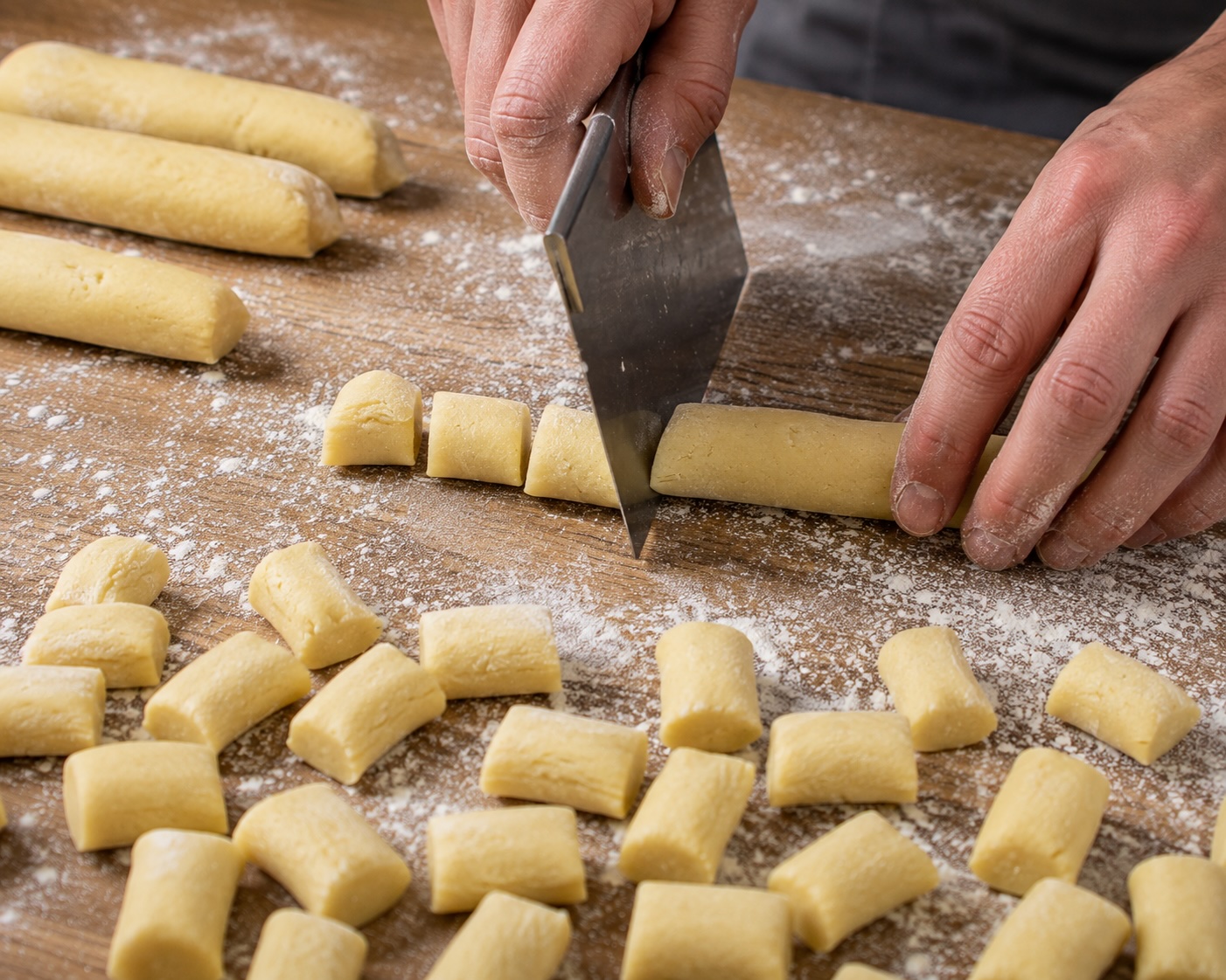 Kartoffelteig wird zu Rollen geformt und mit der Teigkarte in kleine Erdäpfelnudeln geteilt